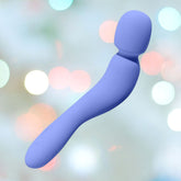 The Dame Com Wand Massager in Periwinkle, featuring a powerful motor and a sleek curved handle with a rounded end, is set against a soft-focus background with circular light bokeh effects.